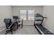 Bedroom features neutral walls and carpet, with an exercise machine, desk and chair, and two windows at 5625 Axil Ln, Charlotte, NC 28269