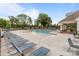 Community pool with lounge chairs, umbrellas, tables and chairs surrounded by mature trees and greenery at 5625 Axil Ln, Charlotte, NC 28269