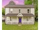 Charming two-story home featuring a covered front porch, white railings, and a vibrant purple front door at 60 Valley Nw St, Concord, NC 28025