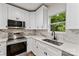 Modern kitchen with white cabinets, stainless steel appliances, granite countertops, and a window overlooking greenery at 60 Valley Nw St, Concord, NC 28025