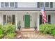 Inviting front porch with a vibrant green door, American flag, and comfortable seating at 618 Heathermoor Ct, Charlotte, NC 28209