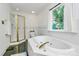 Bathroom featuring a soaking tub with gold fixtures, a window, and a tiled shower at 655 Powder Horn Ln, Indian Trail, NC 28079