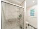 Bright shower with white marble-style tile, glass door and hexagon floor, plus updated fixtures at 6621 Ronda Ave, Charlotte, NC 28211