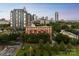 A red brick apartment building is nestled among greenery with downtown buildings in the background at 715 N Church St # 613, Charlotte, NC 28202