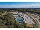 Aerial view of a community with a pool, clubhouse, parking, and tennis courts nestled among trees at 7332 Jolly Brook Dr, Charlotte, NC 28215