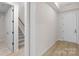 Hallway featuring light wood floors, white trim, door, and ceiling trim detail; stairs in the background at 7332 Jolly Brook Dr, Charlotte, NC 28215