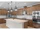Well-lit kitchen with stainless appliances, light wood floors, a gas cooktop, and a large island at 7332 Jolly Brook Dr, Charlotte, NC 28215