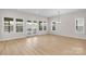 Spacious living room featuring light wood floors, large windows, and bright natural light at 7332 Jolly Brook Dr, Charlotte, NC 28215