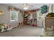 Bright bedroom with plush carpet, ceiling fan, and shelves showcasing an array of toys and natural light from the windows at 844 Fieldstone Rd, Mooresville, NC 28115