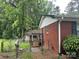 View of the brick home exterior with a small deck and fenced yard surrounded by lush trees at 8524 Anette Ave, Mint Hill, NC 28227