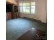 A living room featuring old carpet, dated wallpaper, and a large front window at 8524 Anette Ave, Mint Hill, NC 28227