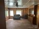 View of the living room with wood paneling, vintage furniture, and ample natural light at 8524 Anette Ave, Mint Hill, NC 28227