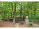 Backyard retreat featuring a wooden swing surrounded by trees and greenery at 9918 Windrow Dr, Indian Trail, NC 28079