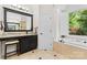 This bathroom features an enclosed tub, standing shower, a large window, and a vanity at 9918 Windrow Dr, Indian Trail, NC 28079