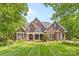 Stunning brick home featuring a meticulously manicured lawn with striped design and mature trees at 9918 Windrow Dr, Indian Trail, NC 28079