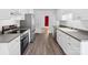 Bright kitchen features stainless steel appliances, gray counters, white cabinets and gray wood-look floors at 1028 Swaying Oats Dr, York, SC 29745