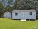 View of two light-blue storage sheds with double doors sitting on a green lawn at 1028 Swaying Oats Dr, York, SC 29745