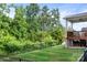 A spacious backyard featuring a black metal fence, lush green lawn, and a covered wooden deck at 10911 Skymont Dr, Huntersville, NC 28078