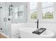 Luxurious bathroom with a soaking tub, glass shower, and natural light streaming through the windows at 10911 Skymont Dr, Huntersville, NC 28078