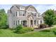 Beautiful two-story home featuring a stone-accented entryway, shuttered windows, and manicured lawn at 10911 Skymont Dr, Huntersville, NC 28078