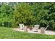 A cozy backyard firepit area with Adirondack chairs, gravel, and privacy from the surrounding mature trees at 10911 Skymont Dr, Huntersville, NC 28078