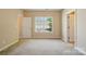 An empty, carpeted bedroom bathed in neutral colors with multiple doorways and a well-lit window at 11209 Lazio Ln # 1, Charlotte, NC 28277