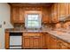 An inviting kitchen with wooden cabinets, double stainless steel sink under a window, and modern dishwasher at 1184 Cambridge Dr, Shelby, NC 28152