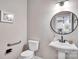 Well-lit half bathroom featuring a pedestal sink, round mirror, and modern fixtures at 1225 Madison Green Dr, Fort Mill, SC 29715