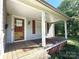 Inviting covered front porch with brick foundation and weathered wood flooring and red shutters at 125 Hunter St, Salisbury, NC 28144