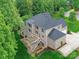 Aerial view of the brick home with a large deck, patio, lush lawn, mature trees, and large driveway at 129 Overlook Ridge Ln, Davidson, NC 28036