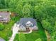 Aerial view of the brick home with a lush green lawn, mature trees, and a large driveway at 129 Overlook Ridge Ln, Davidson, NC 28036