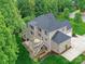 Aerial view of a brick home with a deck and patio surrounded by lush greenery at 129 Overlook Ridge Ln, Davidson, NC 28036