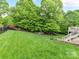 View of a lush green backyard with a wooden deck and a variety of mature trees and landscaping at 129 Overlook Ridge Ln, Davidson, NC 28036