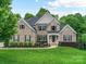 Charming two-story brick home with a manicured lawn and mature landscaping at 129 Overlook Ridge Ln, Davidson, NC 28036