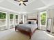 Spacious main bedroom suite featuring tray ceilings and large windows overlooking lush greenery at 129 Overlook Ridge Ln, Davidson, NC 28036