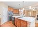 Kitchen island boasts white countertop, stainless steel sink, and wood cabinets, next to stainless fridge at 14104 Kendrick Cross Rd, Charlotte, NC 28273