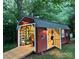 Exterior evening view of a lit shed, featuring a roll-up door, ramp, and wooden door providing ample access at 144 Chickasaw Dr, Shelby, NC 28152
