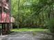 Features a raised home with a brick foundation, a lush green lawn extending into a densely wooded area at 1451 Blueberry Ln, Charlotte, NC 28226