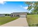 Single-story house featuring a well-maintained lawn and a long driveway leading to an attached garage at 154 Stable Brook Ln, Taylorsville, NC 28681