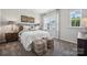 Bright bedroom featuring a large window, carpeted floors, a cozy bed, and lamps at 3125 Beacon Heights Rd, Indian Land, SC 29707