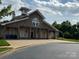 Exterior view of the neighborhood clubhouse featuring a stone facade, wooden accents, and manicured landscaping at 410 Deer Brush Ln, Waxhaw, NC 28173