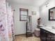 Bright bathroom features a walk-in shower with a patterned curtain, decorative mirror, and neutral tile flooring at 425 Troutman Rd, Rockwell, NC 28138