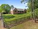 Classic brick home with a metal roof and a sprawling, well-manicured lawn, enhanced by a charming wooden fence at 425 Troutman Rd, Rockwell, NC 28138