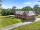 Attractive brick home with metal roof, surrounded by lush greenery and a spacious yard at 425 Troutman Rd, Rockwell, NC 28138