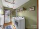 The laundry room features modern washer and dryer units, a rustic shelf with baskets, and hardwood floors at 425 Troutman Rd, Rockwell, NC 28138