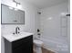 Bright bathroom with dark vanity, and shower-tub combination featuring a rainfall shower head at 4500 Ridgeley Dr, Charlotte, NC 28208