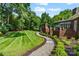 Backyard with winding gravel path leading to a manicured lawn with brick wall in a lush and landscaped setting at 4920 Parview S Dr, Charlotte, NC 28226