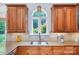 A cozy kitchen showcasing wood cabinets, stainless steel sink, and a large arched window with a backyard view at 552 Wyndham Ln, Marvin, NC 28173