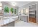 Bright bathroom with a soaking tub, dual vanities, a large window, and an attached walk-in closet at 5601 Robinhood Rd, Charlotte, NC 28211