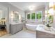 Bright bathroom with a soaking tub, dual vanities, a large window, and stylish gold light fixtures at 5601 Robinhood Rd, Charlotte, NC 28211